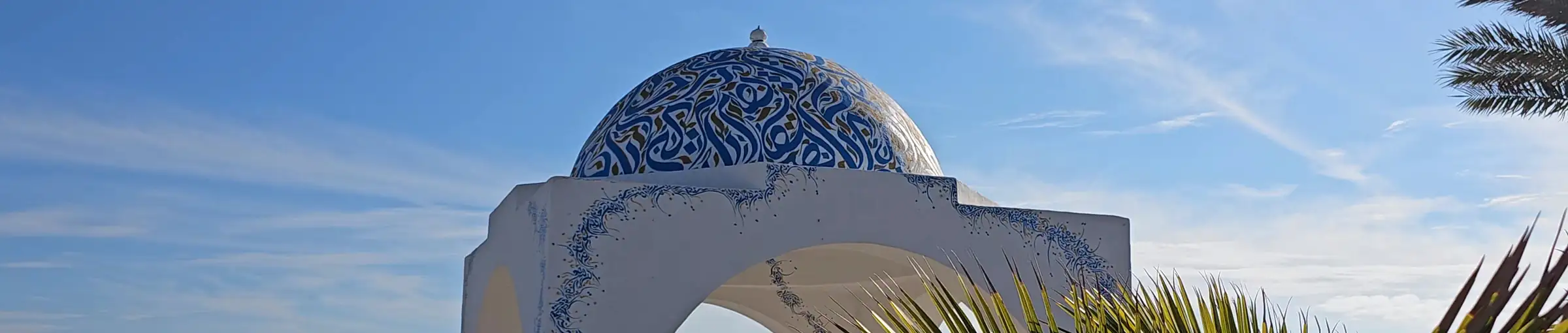 Arche et coupole bleue à motifs face à la mer à Hammamet, palmes au premier plan